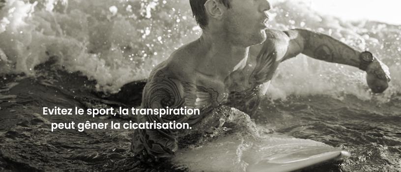Homme tatoué qui fait du sport Homme tatoué qui pratique le surf pour illuster qu'il faut éviter de faire du sport après un tatouage
