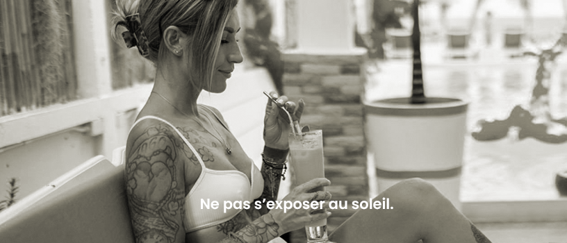 Femme tatouée au soleil Une femme tatouée qui sirote un cocktail au soleil afin d'imager qu'il ne faut pas exposer ses tatouages au soleil