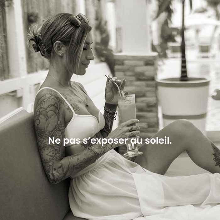 Femme tatouée au soleil Une femme tatouée qui sirote un cocktail au soleil afin d'imager qu'il ne faut pas exposer ses tatouages au soleil